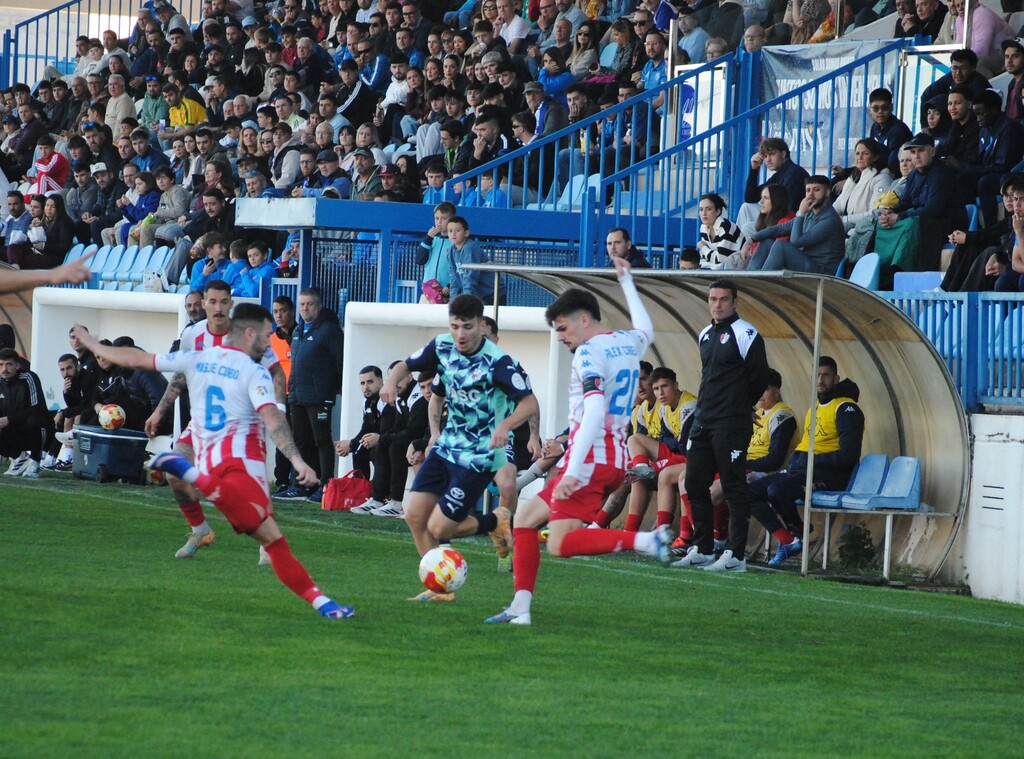 Migue Cobo y Álex Cabello, dos ex del Motril intentan despejar el balón antes de que lo alcance Nieto